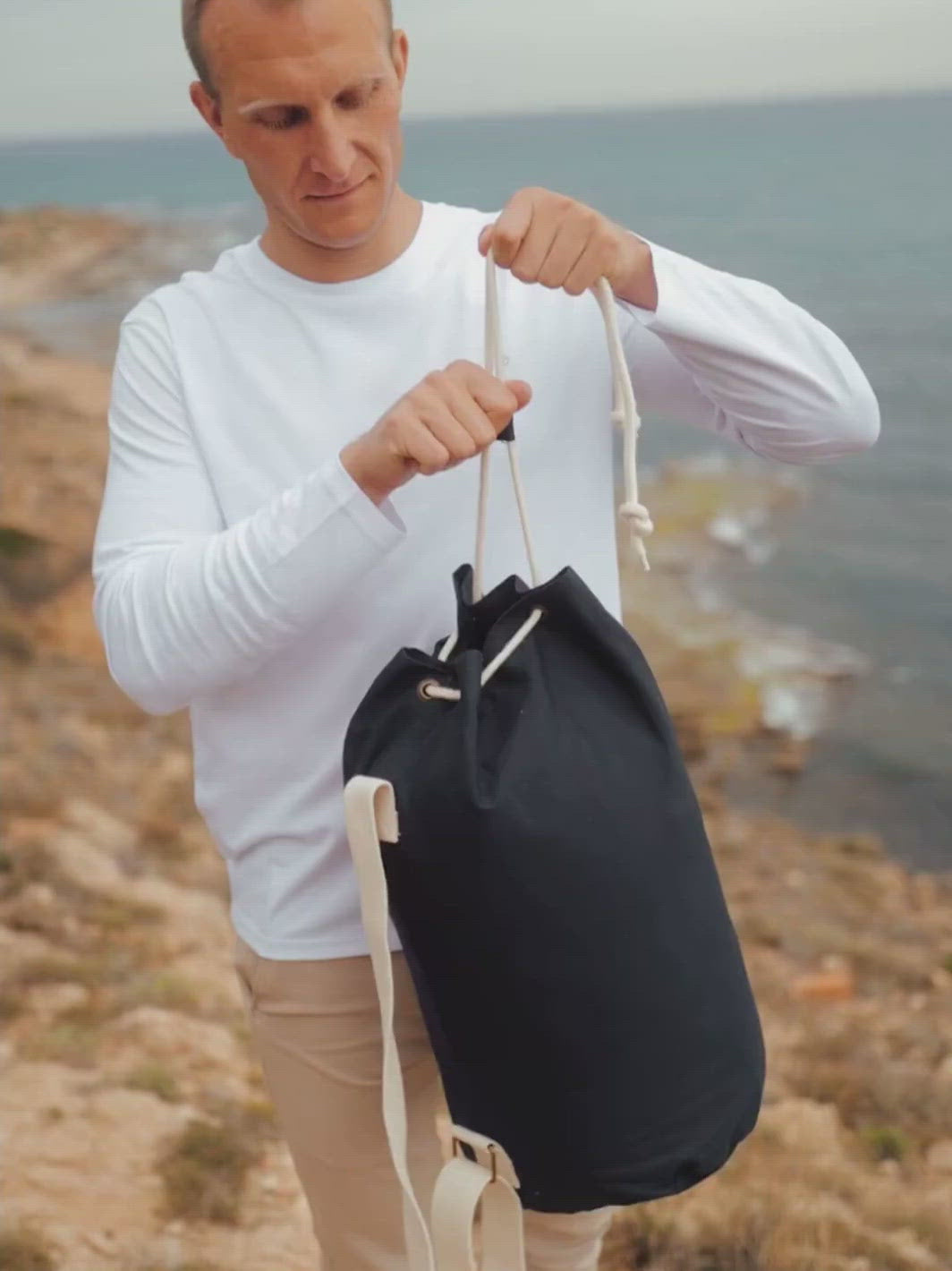 Marine plátěná taška z biobavlny námořní modrá muž stojí na útesu kde si přehazuje tašku přes rameno