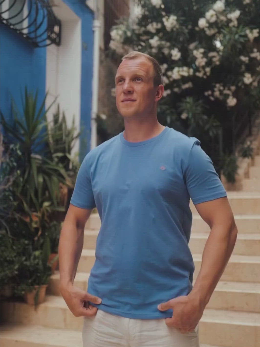 Feel pánské tričko z biobavlny s kulatým výstřihem modré muž si upravuje tričko na schodišti)