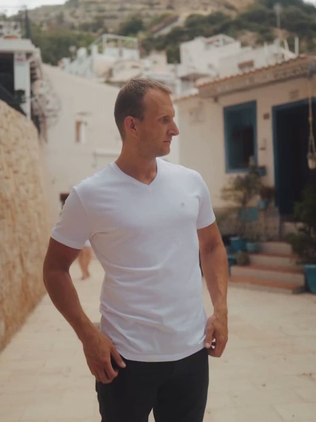Sanremo pánské tričko s výstřihem do V z biobavlny bílé muž pózuje ve městě s rukama v kapse