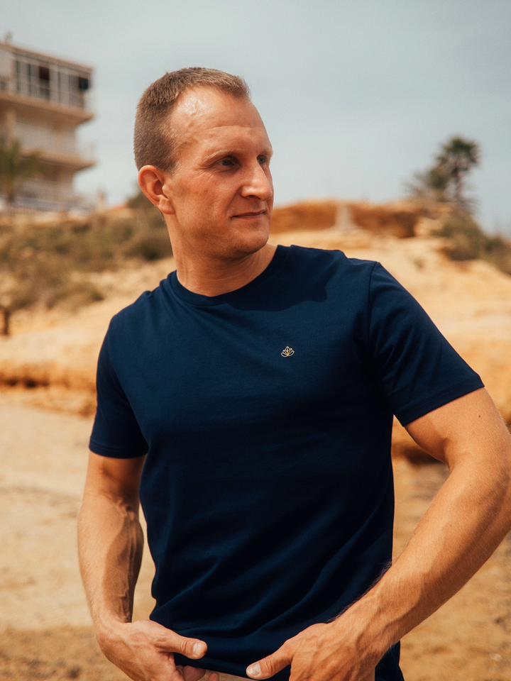 Feel pánské tričko z bio bavlny s kulatým výstřihem námořní modré muž stojí před domem s vyšívaným logem na hrudi
