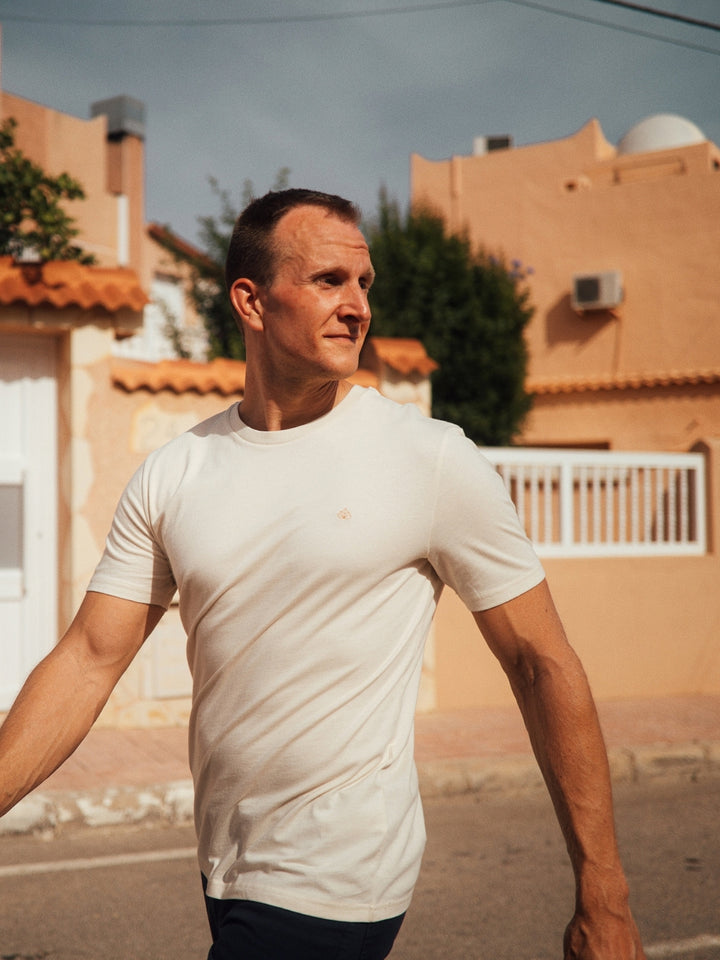 Feel pánské tričko z biobavlny s kulatým výstřihem přírodní nebarvené muž jde po ulici a ohlíží se přes rameno