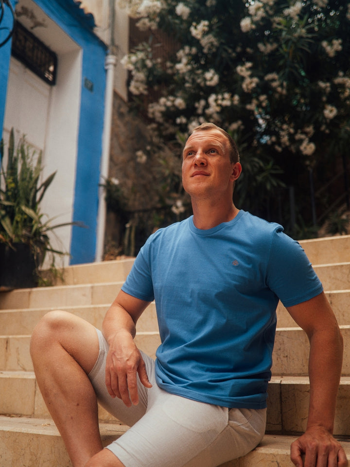 Feel pánské tričko z biobavlny s kulatým výstřihem modré muž sedí na schodech