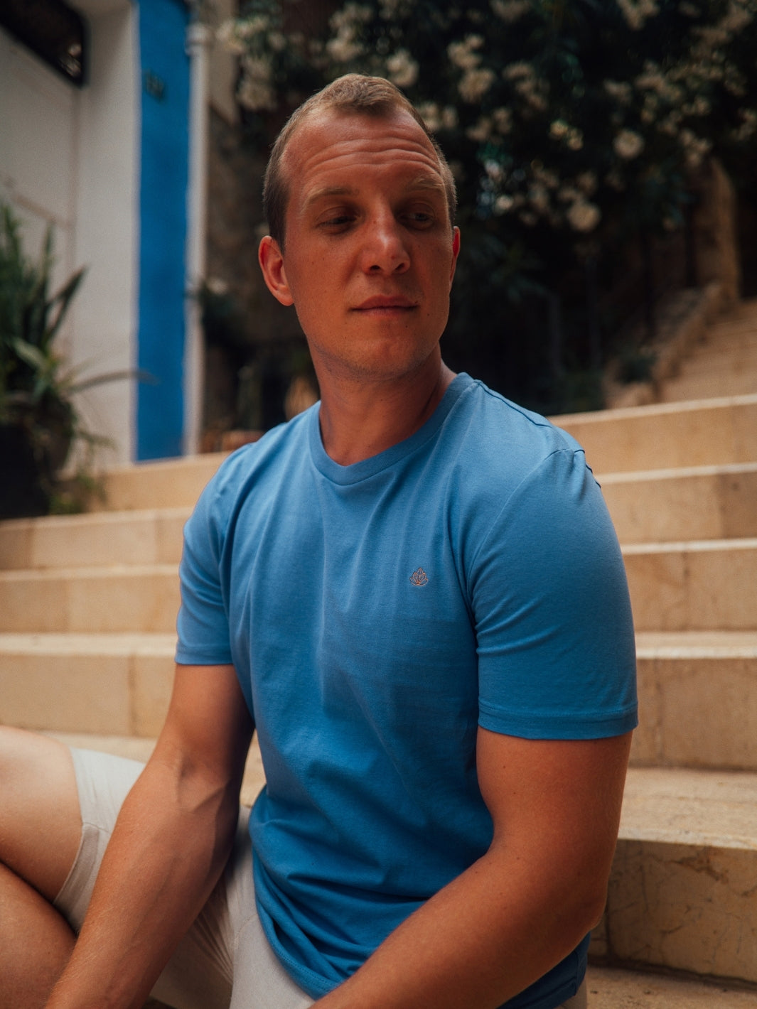 Feel pánské tričko z biobavlny s kulatým výstřihem modré muž sedí s vyšívaným logem na hrudi