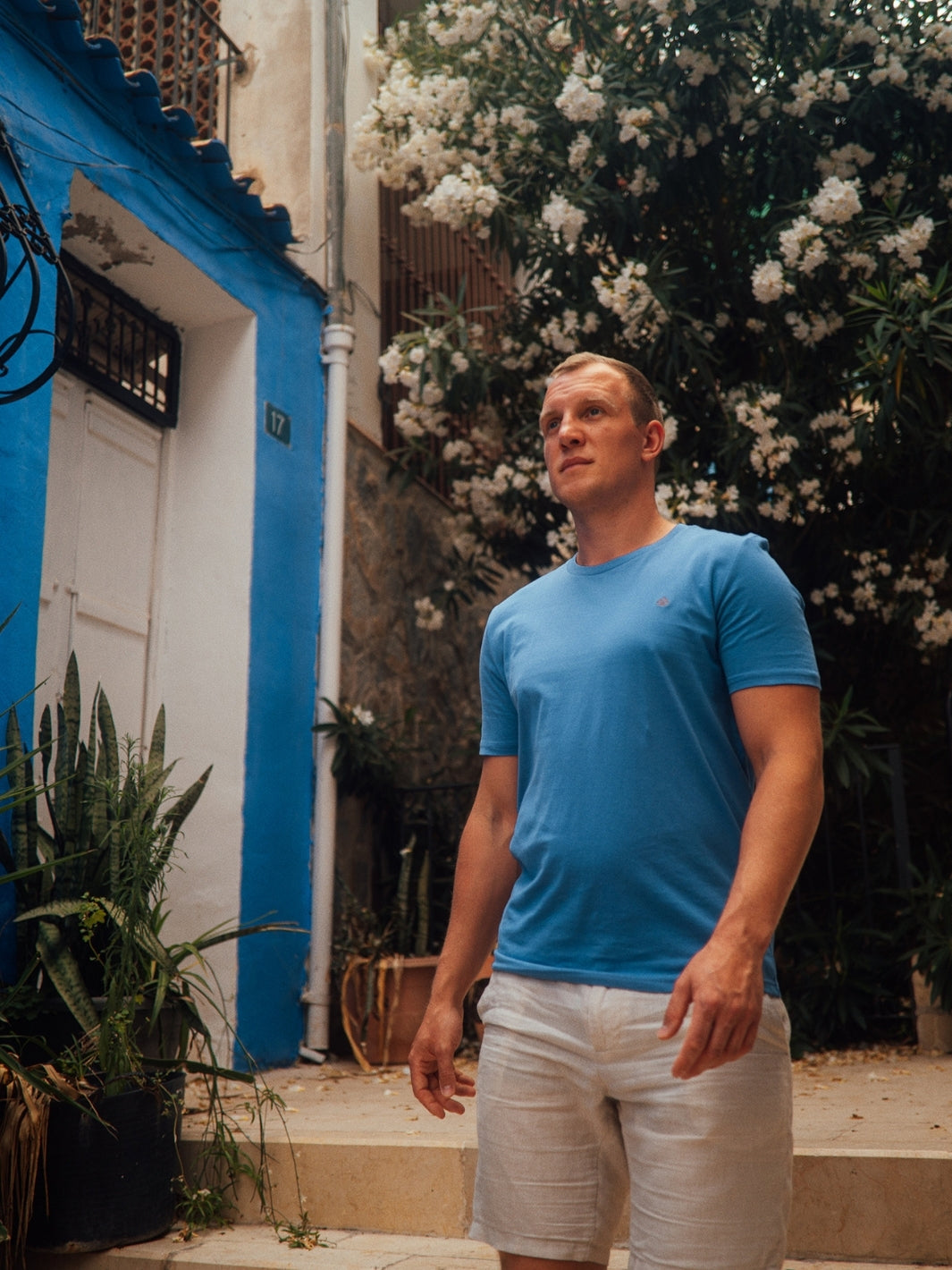 Feel pánské tričko z biobavlny s kulatým výstřihem modré muž jde po schodech kolem keře