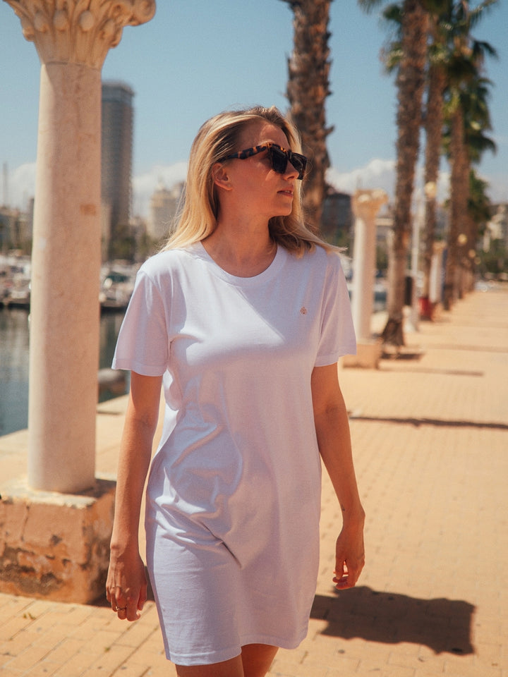 Marbella dámské letní šaty z biobavlny bílé kulatý výstřih s rukávy žena jde na molu v přístavu