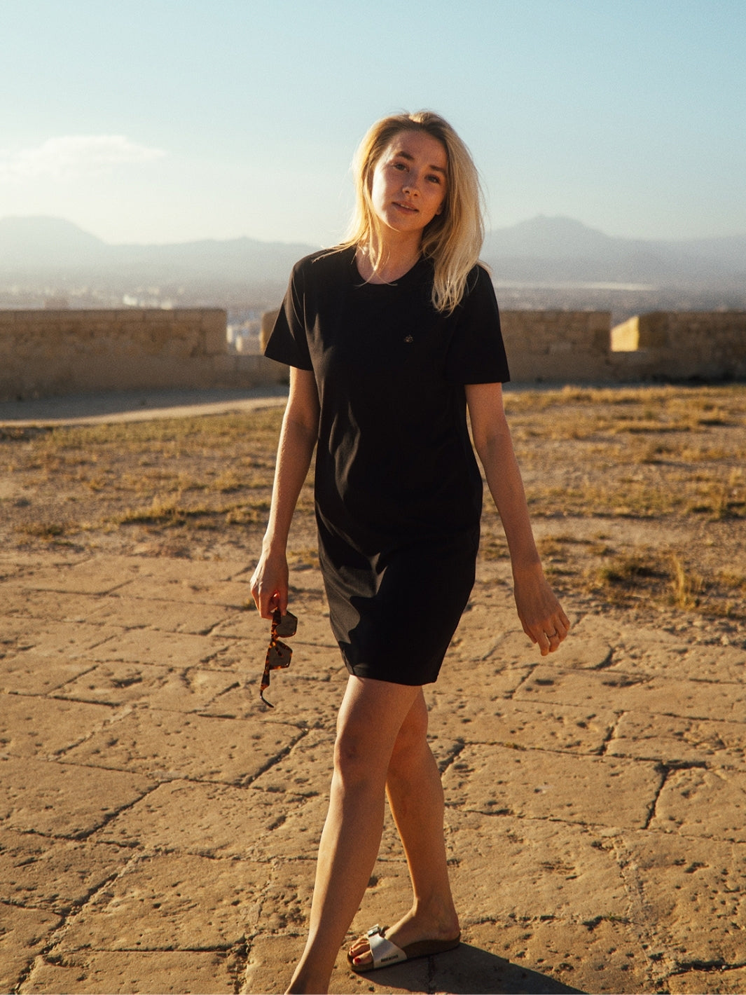 Marbella dámské letní šaty z biobavlny černé kulatý výstřih s rukávy modelka s modrým nebem