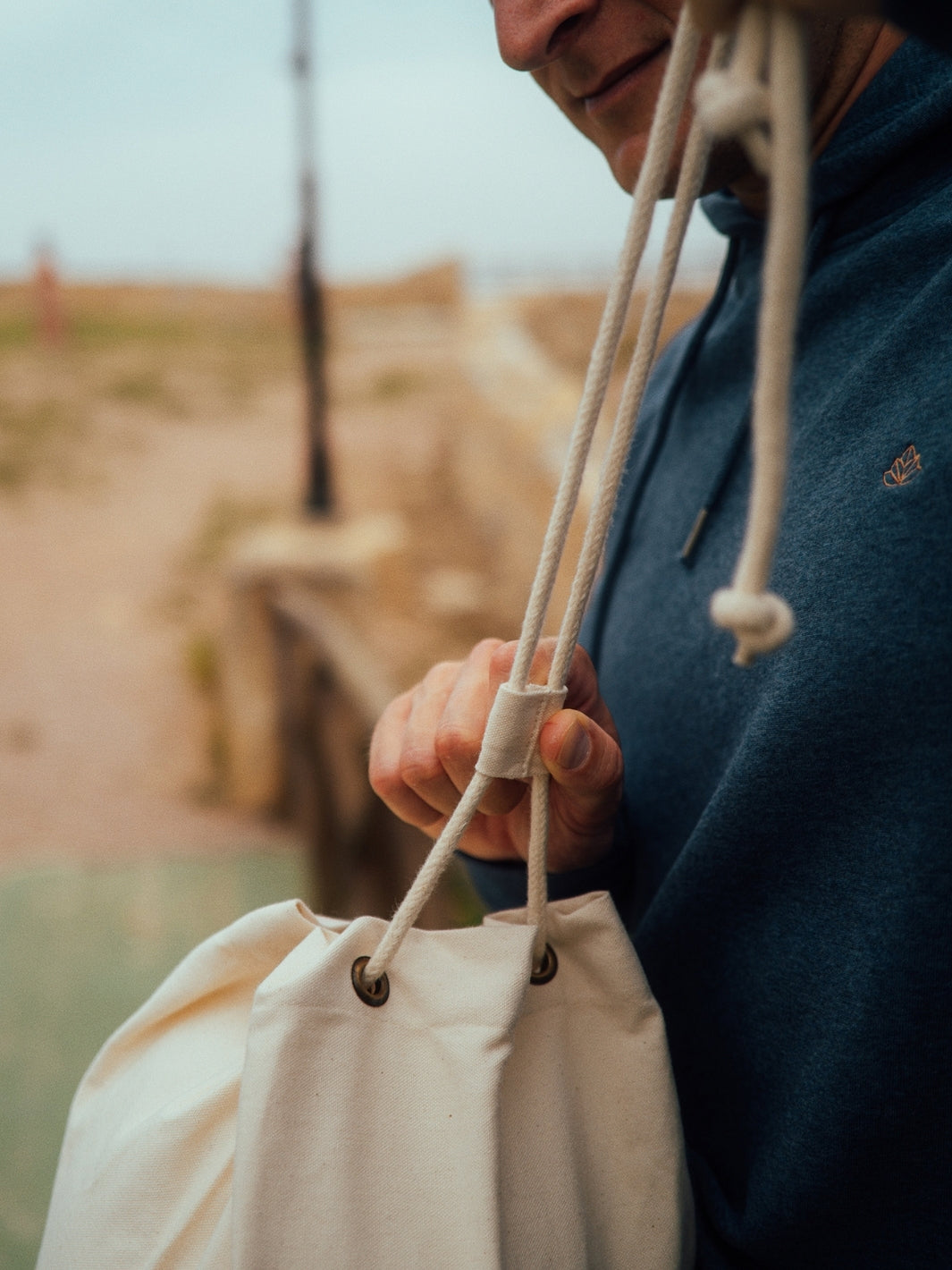 Marine plátěná taška z biobavlny přírodní nebarvená muž utahuje šňůrky na tašce
