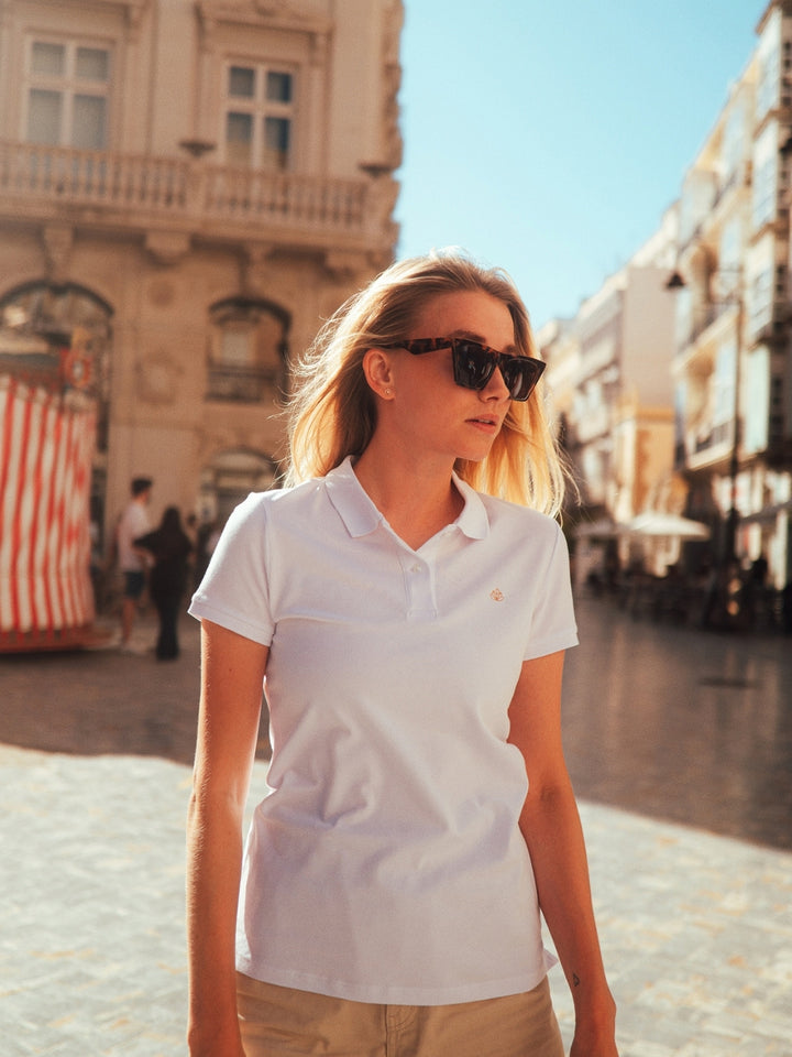 Milano dámské polo tričko z biobavlny bílé blondýnka jde po městě s modrým nebem