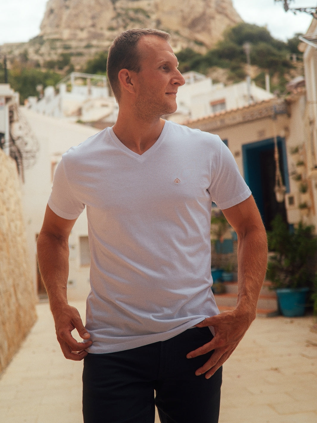 Sanremo pánské tričko s výstřihem do V z biobavlny bílé muž ve městě s rukama v kapse