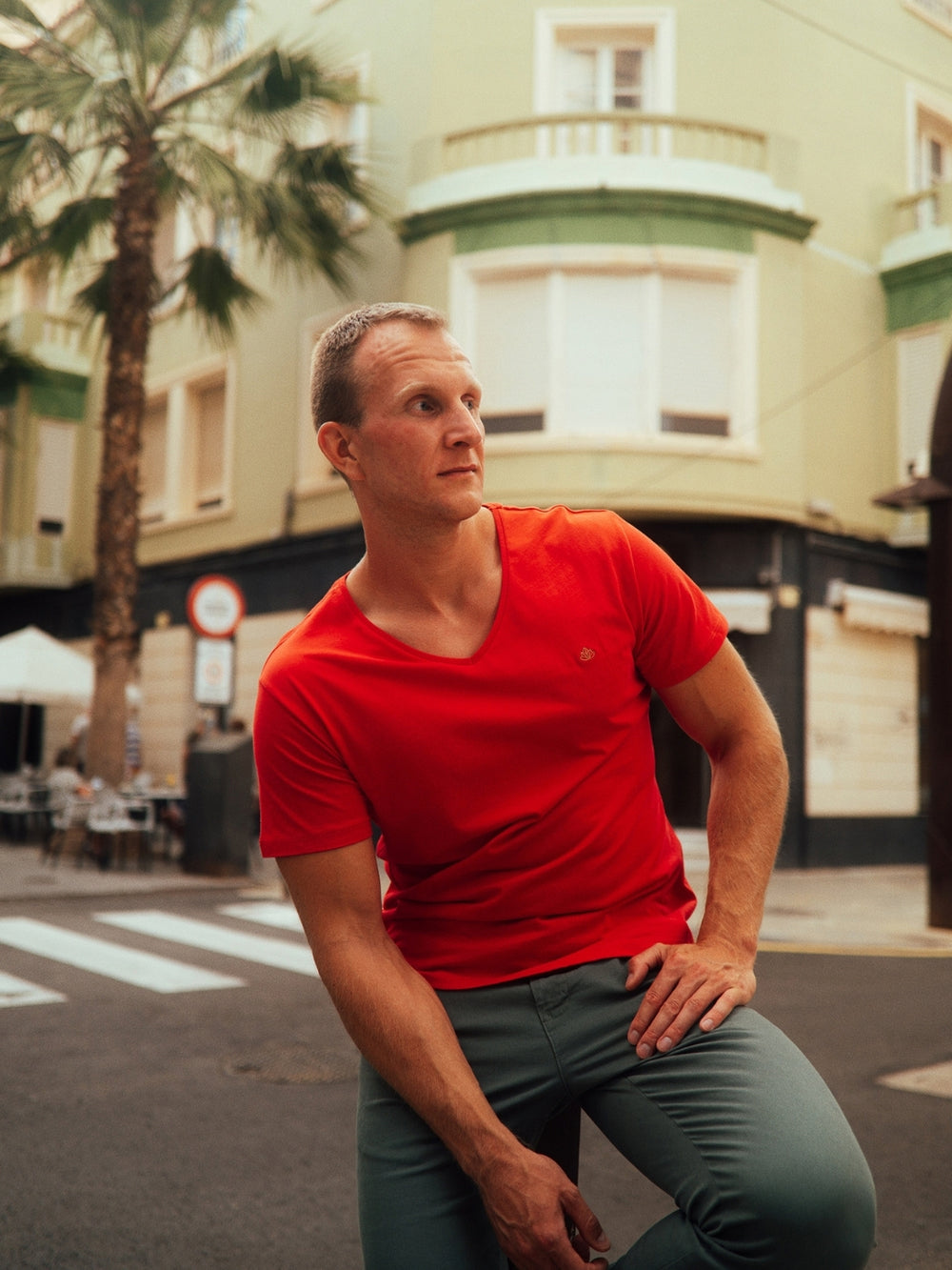 Sanremo pánské tričko s výstřihem do V z biobavlny červené muž sedí na ulici