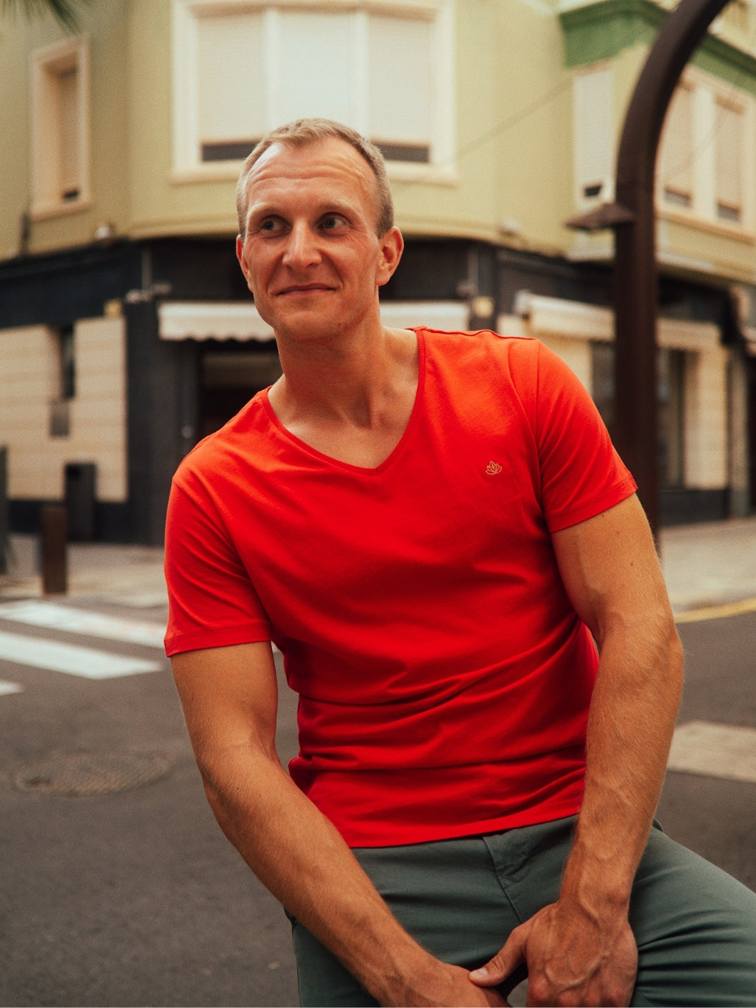Sanremo pánské tričko s výstřihem do V z biobavlny červené muž sedí na ulici a dívá se před sebe